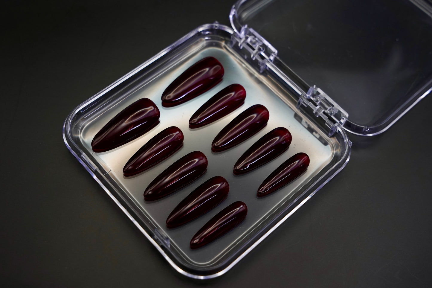 Et komplett Cherry on Top negle sett med glossy, røde negler vist fra siden i emballasjen, som viser den glassaktige, høyglans finishen.