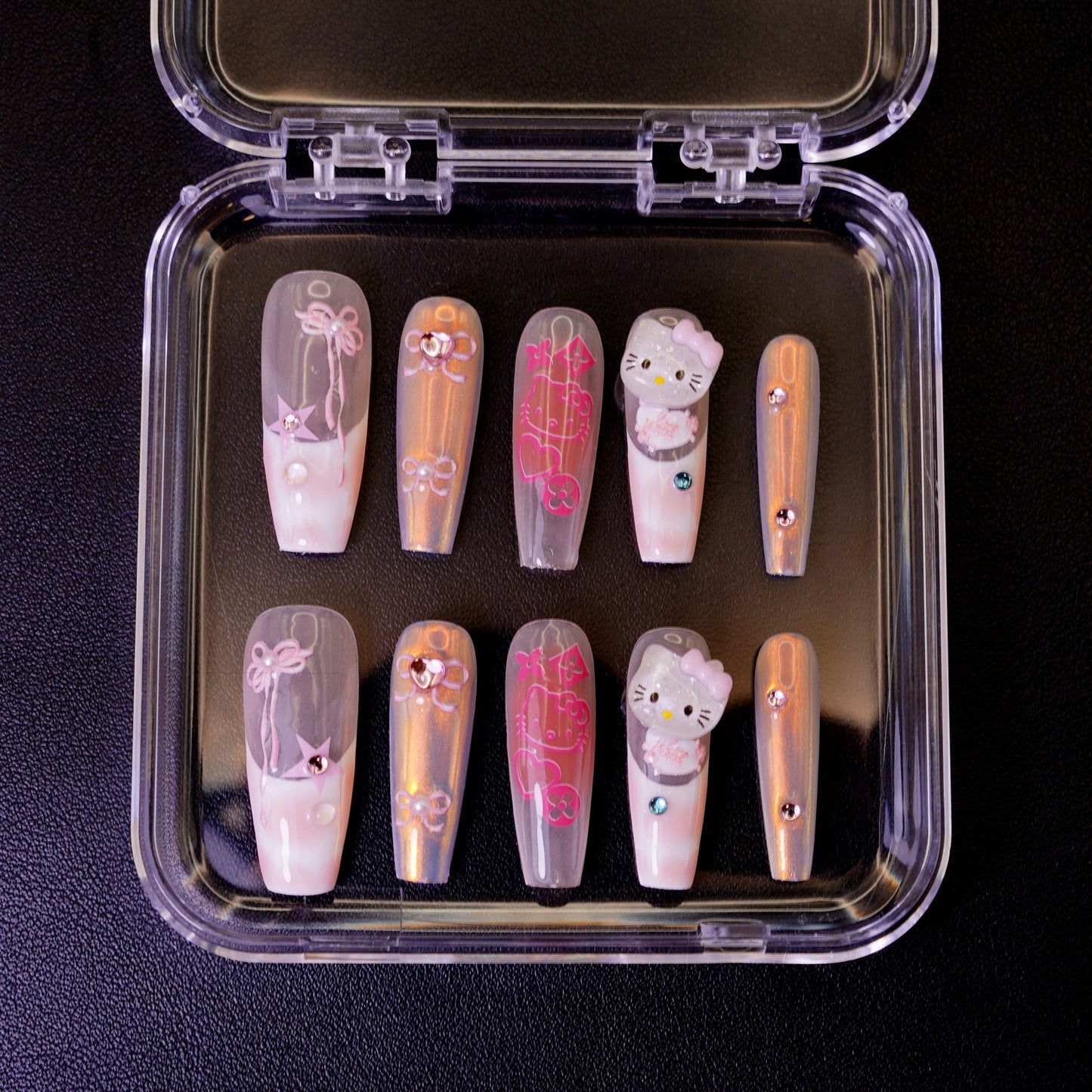 Top-down view of the Y2K Royalty false nails set, showing intricate details like 3D Hello Kitty faces, pink bow designs, and a holographic chrome finish.