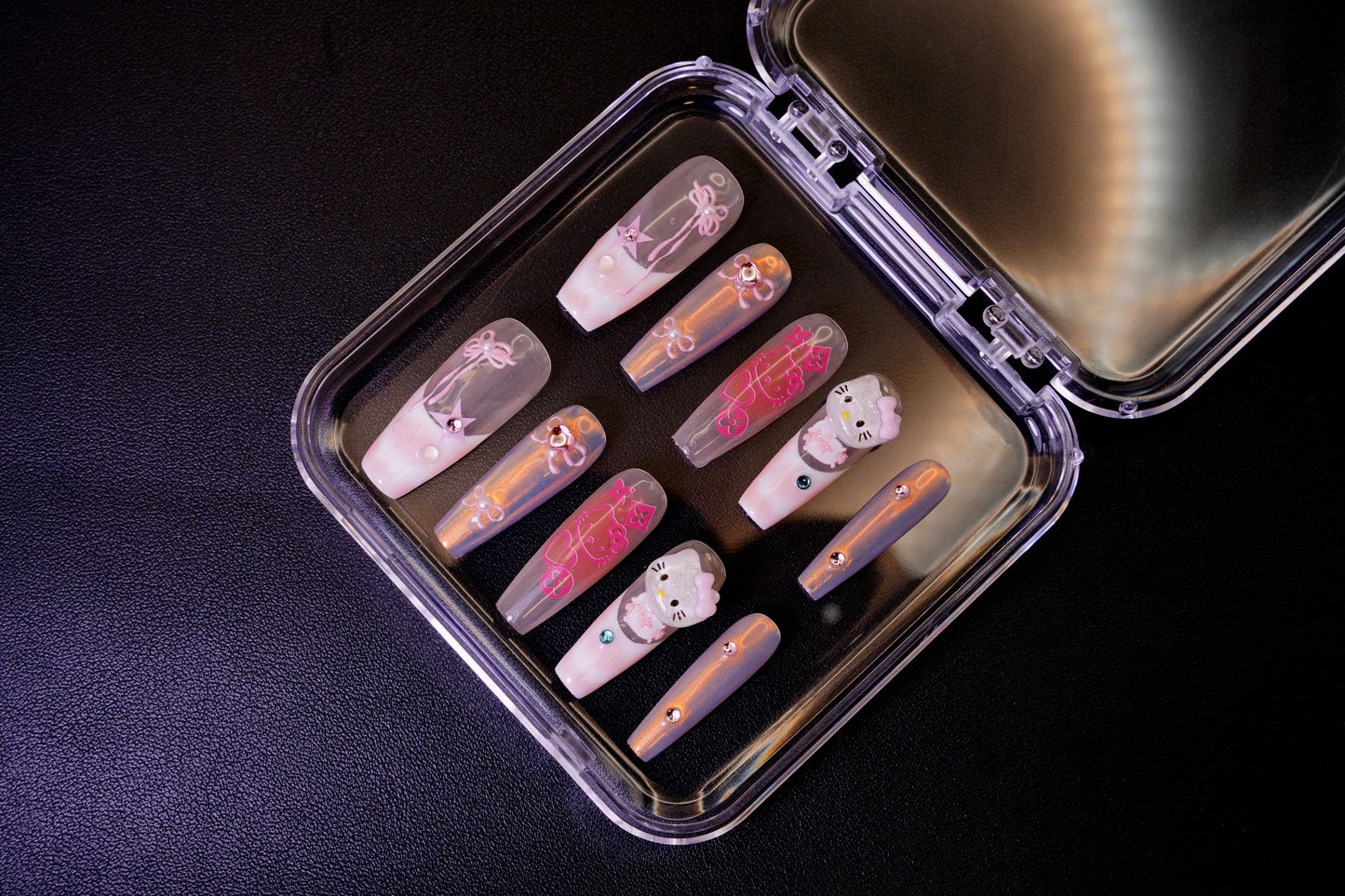 The Y2K Royalty nail set displayed from the side in its packaging. The holographic pink and chrome nails are shown with their 3D Hello Kitty and rhinestone details.