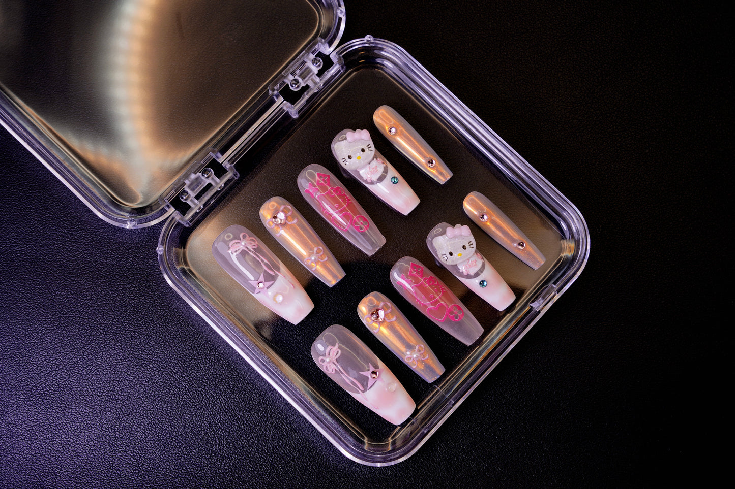 Angled view of the Y2K Royalty press-on nails in their open case. The set features long ballerina-shaped nails with a holographic finish and 3D Hello Kitty charms.