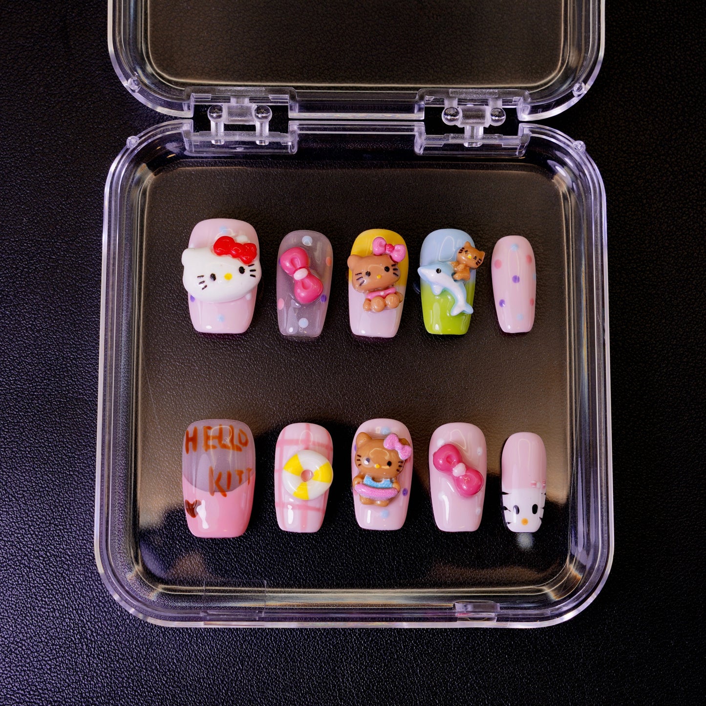 Ovenfra-bilde av Kitty Island press on negler i etui. Viser de mange 3D-figurene, inkludert Hello Kitty, en delfin, og en livbøye for en tropisk følelse.