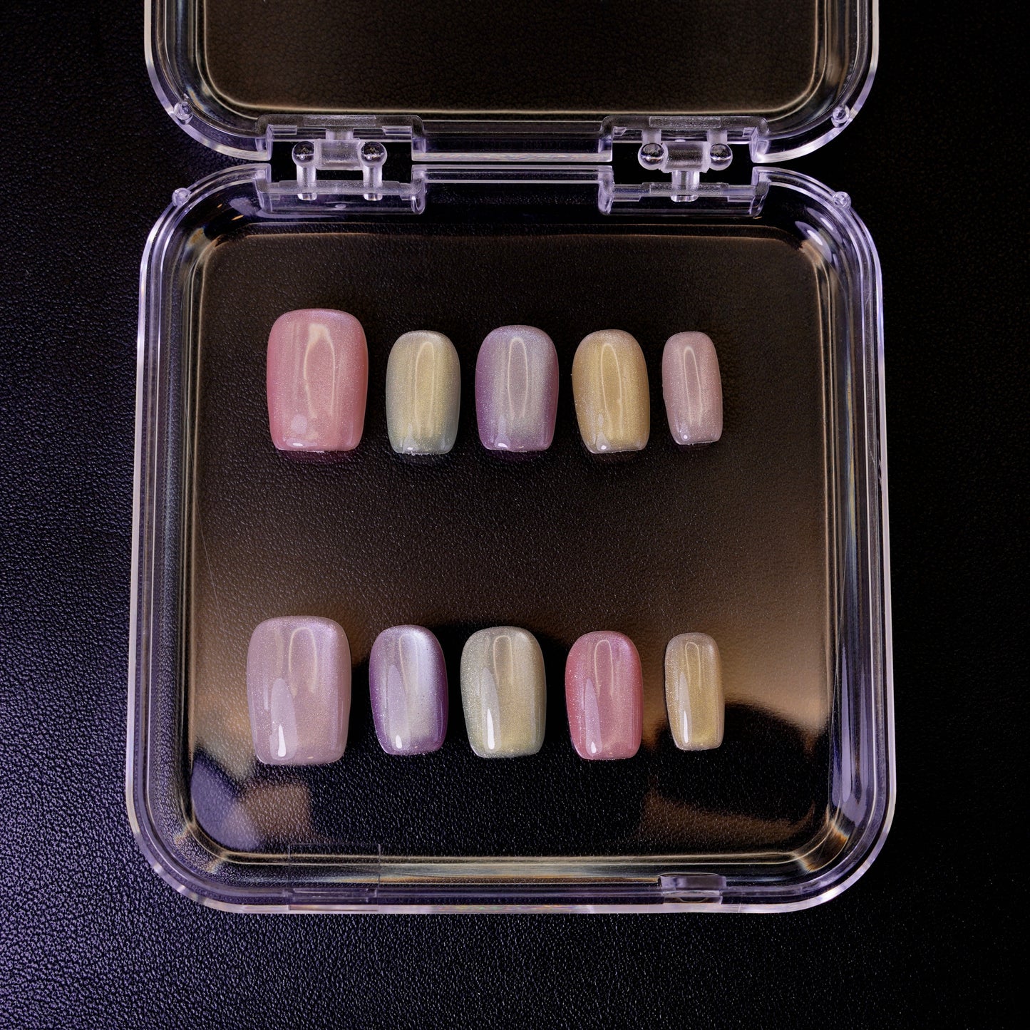 Ovenfra-bilde av Cotton Candy press on negler i etui. De firkantede neglene viser en myk, pastellfarget cat-eye-effekt.