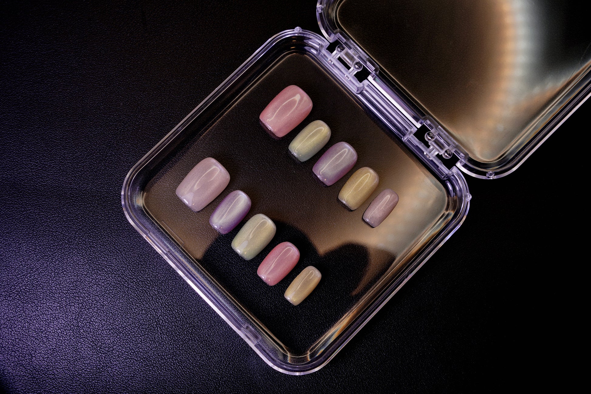 Vinklet bilde av Cotton Candy løsnegler. Viser den skinnende cat-eye-effekten på de pastellfargede, firkantede neglene.