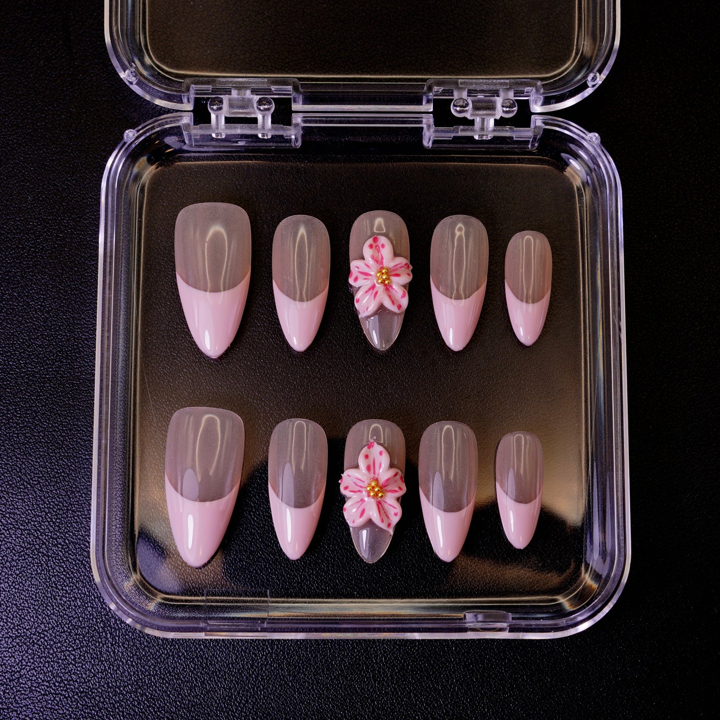 Ovenfra-bilde av Bloom Baby Bloom press on negler i etui. Viser de mandelformede neglene med en myk, rosa French fade og en 3D-blomst.