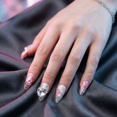 Close-up of a hand with Pretty in pain press on nails on a dark fabric background