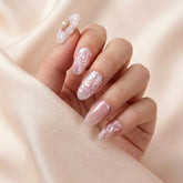 Hånd på lyserosa silkestoff med Flower Therapy press on negler — håndlaget, gjenbrukbare runde negler med 3D blomst-charm, chrome bølger og perle-glitter accent.