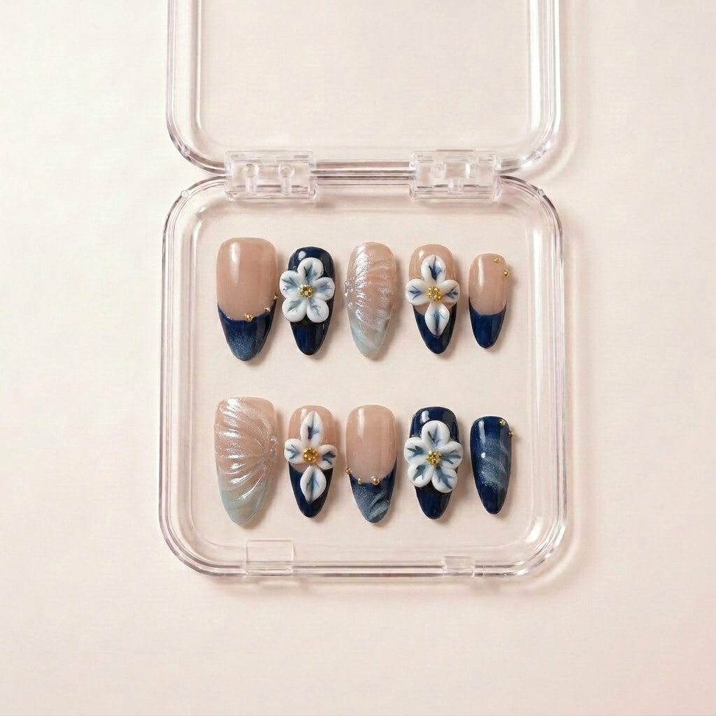 Hardanger Heiress press on nails i etui — håndlaget almond-negler med dyp marineblå ombré-tipp, 3D blå-hvite blomster med gull i hjertet, og en perlemor-aksent.