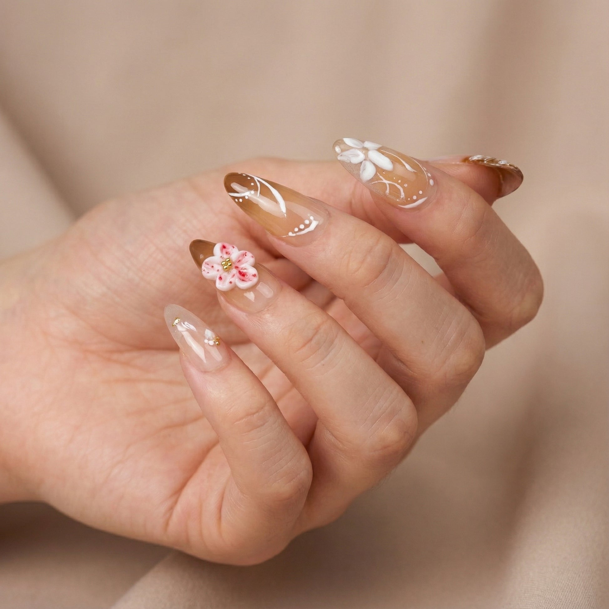 Close-up of a hand with Coastal bloom press on nails on a beige background