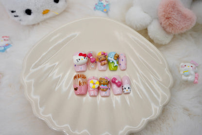 Stylet bilde av Kitty Island press on negler for en full 'kawaii dream'-look. Neglesettet er presentert på et hvitt skjell-fat, omgitt av små Hello Kitty-figurer.
