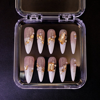 Ovenfra-bilde av Gold Digger's Gala press on negler i etui. Viser de lange stiletto-neglene med store, gullfargede edelstener og perler.