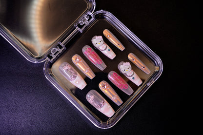 Angled view of the Y2K Royalty press-on nails in their open case. The set features long ballerina-shaped nails with a holographic finish and 3D Hello Kitty charms.