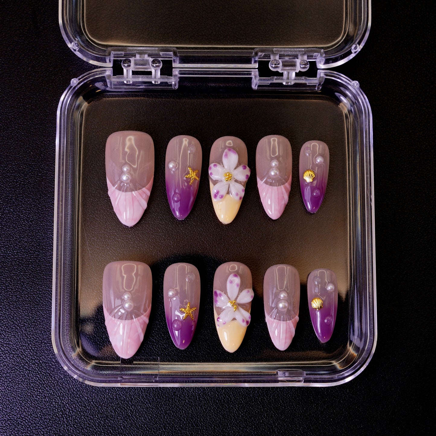 Ovenfra-bilde av Siren's Blush press on negler i etui. De mandelformede neglene har en pastell-gradient med 3D-blomster og perle-detaljer.