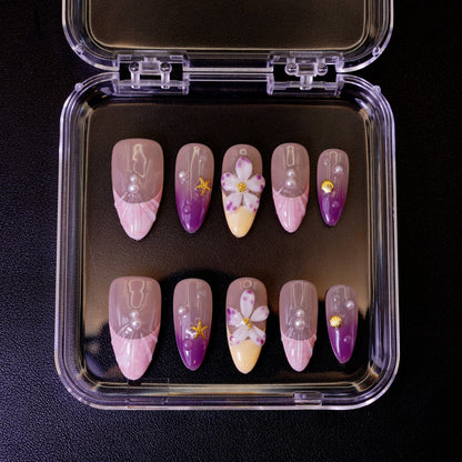 Ovenfra-bilde av Siren's Blush press on negler i etui. De mandelformede neglene har en pastell-gradient med 3D-blomster og perle-detaljer.