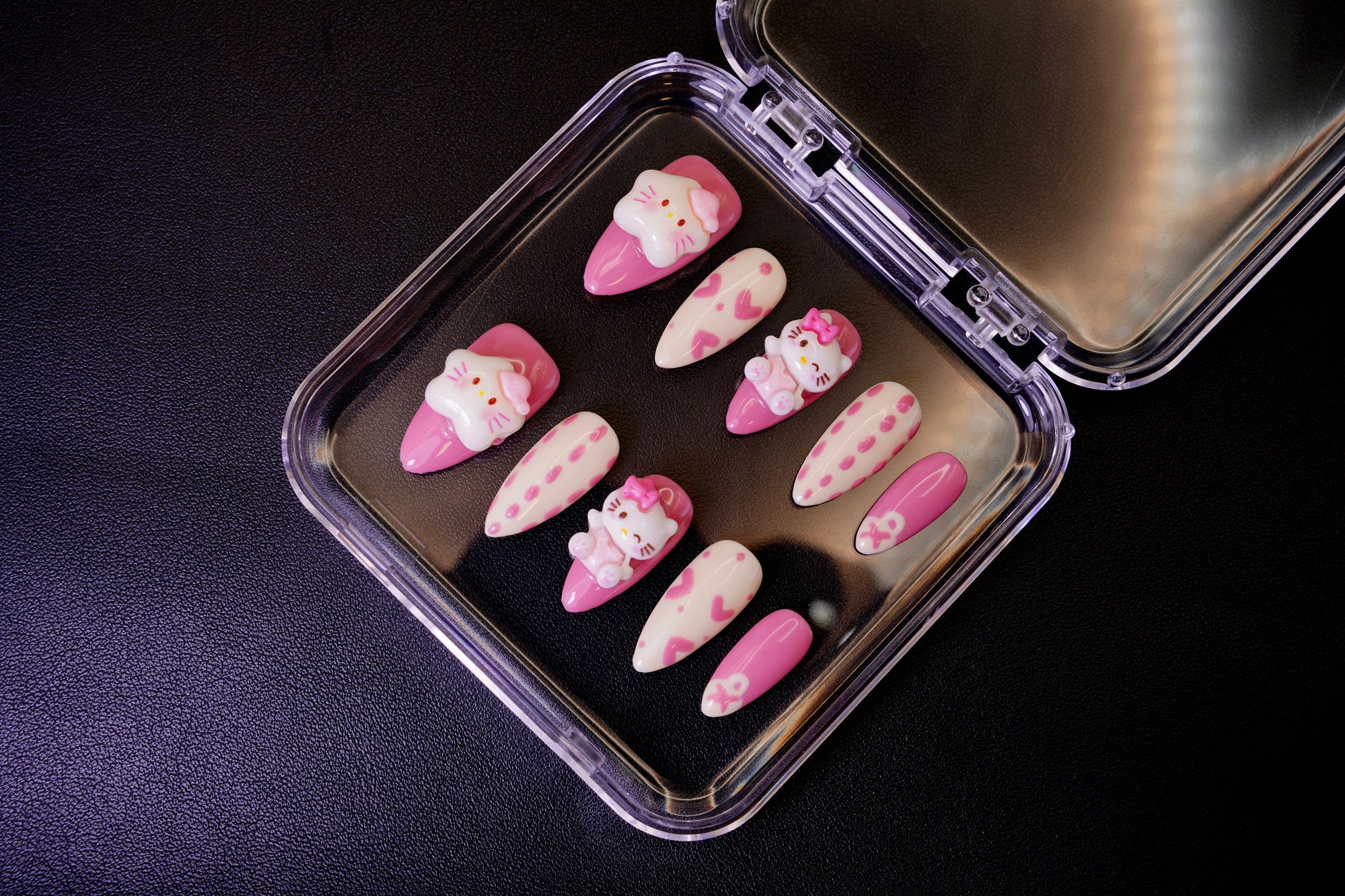 Vinklet bilde av Kawaii Crisis løsnegler. De pastellfargede neglene er dekorert med store, kawaii 3D-charms som Hello Kitty.