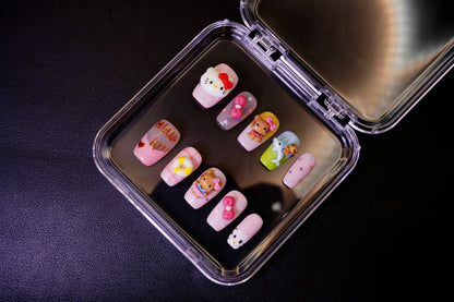 Vinklet bilde av Kitty Island løsnegler. De fargerike, korte neglene har kawaii 3D-charms med Hello Kitty-tema.