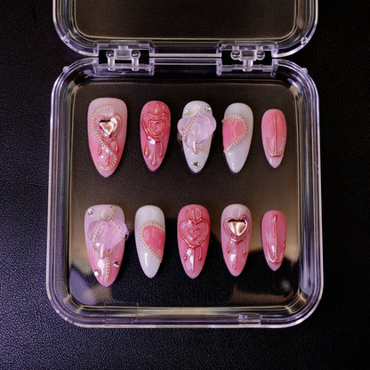 Ovenfra-bilde av Pretty in Pain press on negler i etui. Viser de mandelformede neglene med design av knuste hjerter, krom-hjerter og sølvlenker.