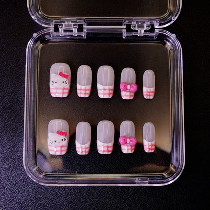 Ovenfra-bilde av Gingham Kitty press on negler i etui. Viser de firkantede neglene med rosa gingham-mønster, Hello Kitty-ansikter og 3D-sløyfer.