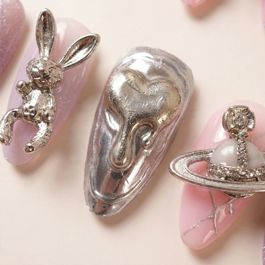 Makro-nærbilde av Astro Bunny løsnegler — falske negler med lim, med 3D bunny-figurer, planet-charms og chrome metallic detaljer på rosa base.