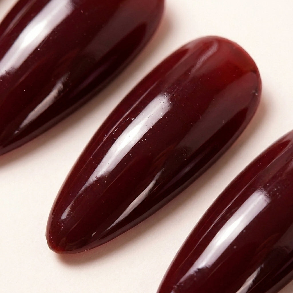 Makro-nærbilde av Cherry on Top løsnegler — falske negler med lim, med glossy jelly cherry-rød finish uten ekstra detaljer, minimalist stiletto-form.