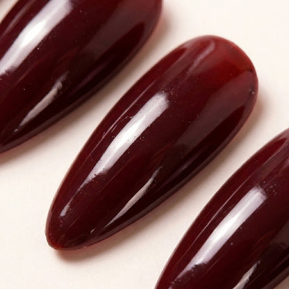 Makro-nærbilde av Cherry on Top løsnegler — falske negler med lim, med glossy jelly cherry-rød finish uten ekstra detaljer, minimalist stiletto-form.