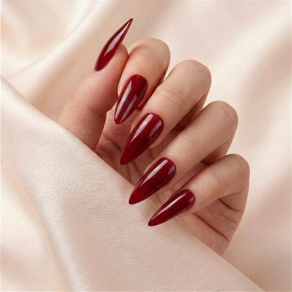 Hånd på beige silkestoff med Cherry on Top press on negler — håndlaget, gjenbrukbare extra lange stiletto-negler i cherry-rød glossy jelly-finish.