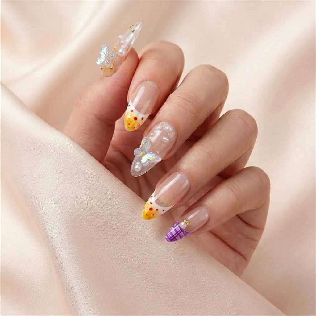 Hånd på lyserosa silkestoff med Coastal Bloom press on negler — håndlaget, gjenbrukbare almond-negler med 3D iridescent sommerfugler, perler og oransje-gul French tip.