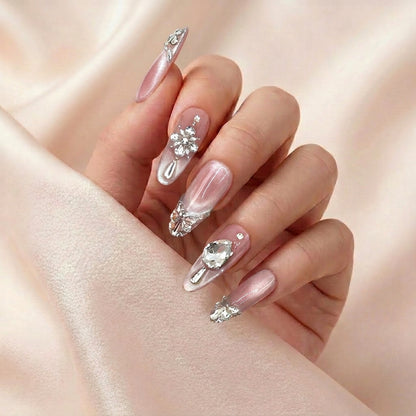 Hånd med Diamond Affair press on negler — gjenbrukbare nude almond-negler med krystaller og glitter-French.