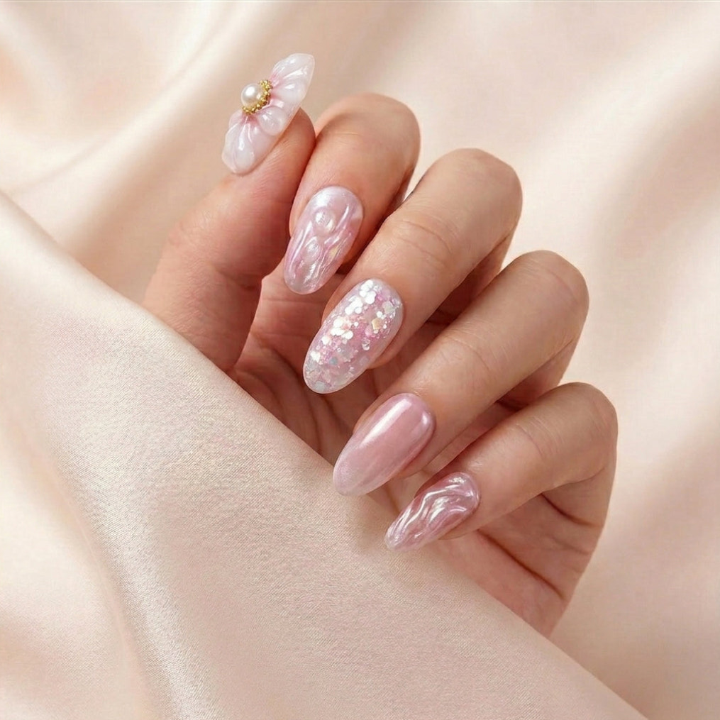 Hånd på lyserosa silkestoff med Flower Therapy press on negler — håndlaget, gjenbrukbare runde negler med 3D blomst-charm, chrome bølger og perle-glitter accent.