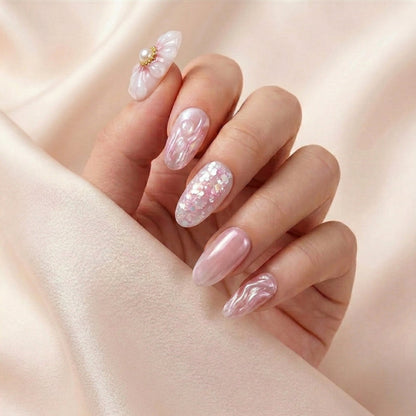 Hånd på lyserosa silkestoff med Flower Therapy press on negler — håndlaget, gjenbrukbare runde negler med 3D blomst-charm, chrome bølger og perle-glitter accent.