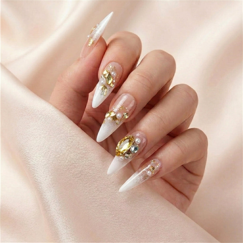 Hånd på lyserosa silkestoff med Gold Digger's Gala press on negler — håndlaget, gjenbrukbare stiletto-negler med stor gull gem-accent, perler og champagne ombré.