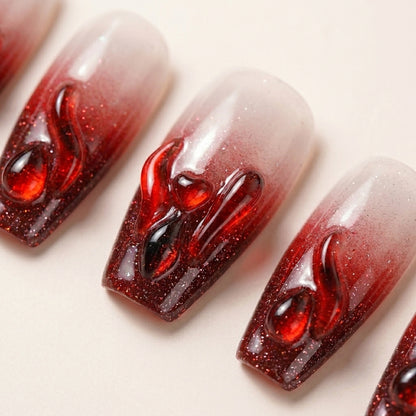 Makro-nærbilde av Hotter Than Revenge løsnegler — falske negler med lim, med håndmalte 3D drip-detaljer i glossy blodrød over skimrende glitter-ombré base.