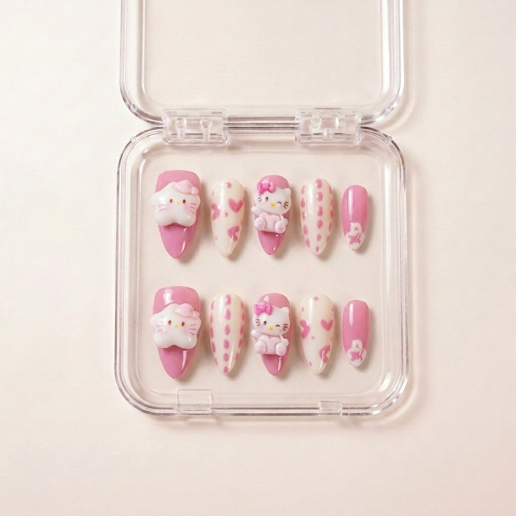 Kawaii Crisis press on nails i etui — håndlaget almond-formede negler med rosa og kremfarget base, håndmalte hjerter og Hello Kitty 3D charms.