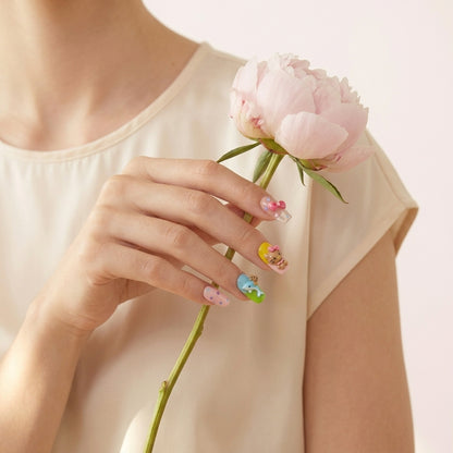 Styled shot med lyserosa peonie og silkebluse — Kitty Island løsnegler i almond-form med 3D Hello Kitty, bamse- og sløyfe-charms, håndlaget med kawaii-tema.