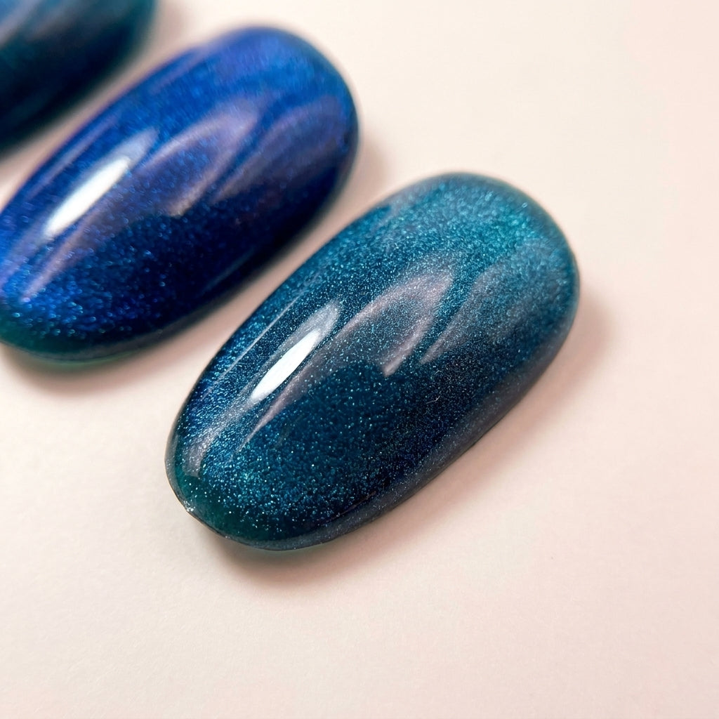 Makro-nærbilde av Ocean Eyes løsnegler — magnetisk cat-eye-effekt i sølvblå og dyp teal.
