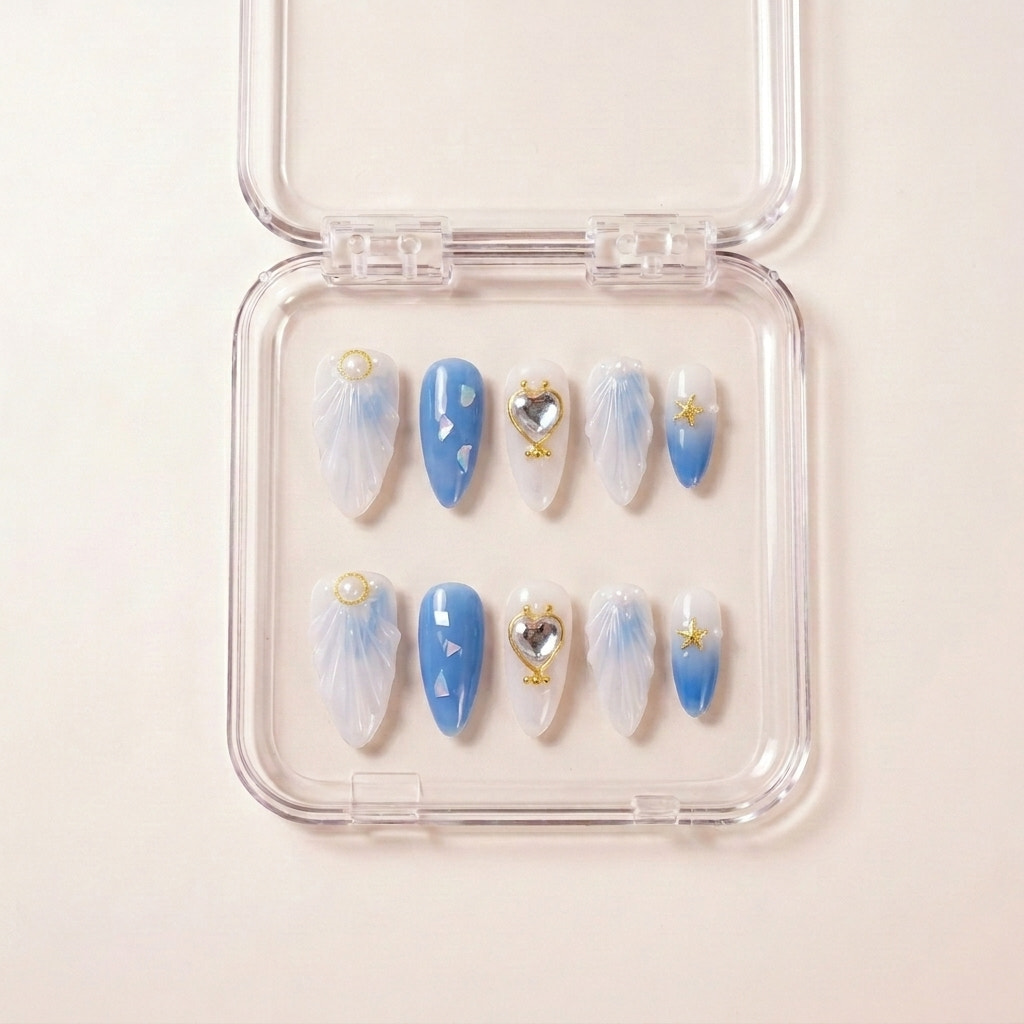 See Me Glow press on nails i etui — håndlaget almond-negler med perle-hvit og blå ombré, 3D sjell-teksturer, krystall hjerte i gullramme og små gullstjerner.