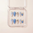 See Me Glow press on nails i etui — håndlaget almond-negler med perle-hvit og blå ombré, 3D sjell-teksturer, krystall hjerte i gullramme og små gullstjerner.