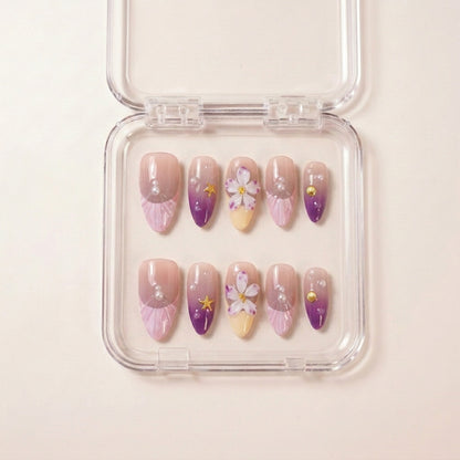 Siren's Blush press on nails i etui — håndlaget almond-negler med lilla ombré, seashell rosa, 3D hvite blomster, perler, sjell-charms og gullfargede sjøstjerner.