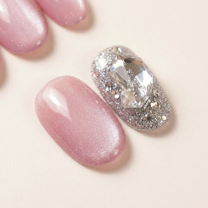 Makro-nærbilde av Stardust løsnegler — falske negler med lim, med satiny mauve pearl base ved siden av glitter-accent med 3D krystall-gem og sølvfarget glitter.