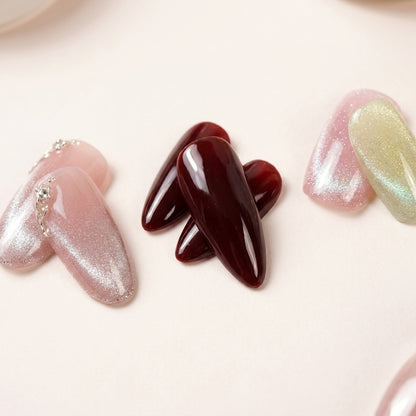Makro-nærbilde av The Minimalist Edit-nagler — Angel Glaze med sølv glitter-ombré og kjede-detalj, Cherry on Top i dyp glossy burgunder og Cotton Candy i pastell chrome.