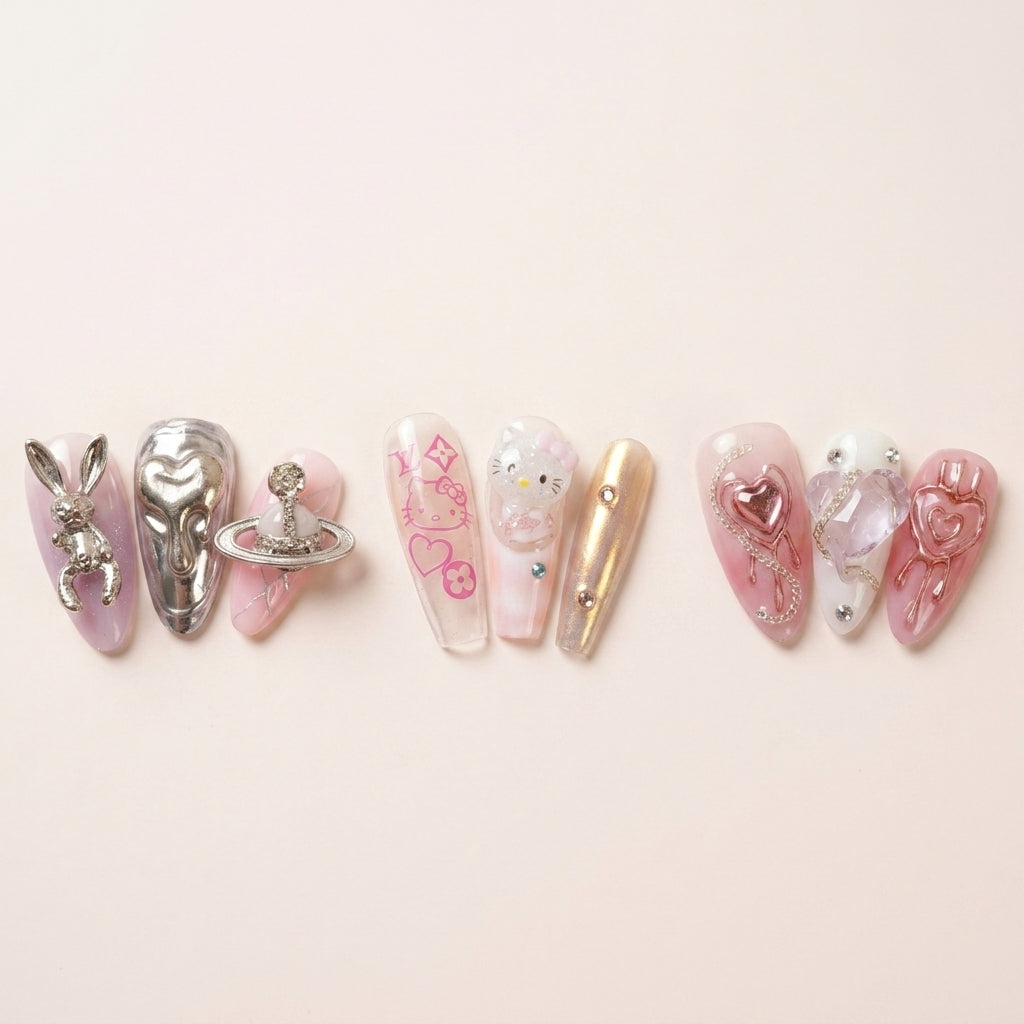 Nærbilde-triptyk av The Y2K Edit-nagler — Astro Bunny med sølv kanin og Saturn-charm, Y2K Royalty med Hello Kitty og logo-print, Pretty in Pain med rosa chrome-hjerter.