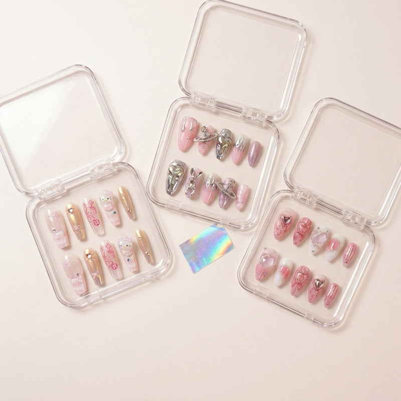 The Y2K Edit styled shot — tre transparente esker med Y2K Royalty rosa chrome-negler med Hello Kitty, Astro Bunny sølv kanin-charms og Pretty in Pain rosa hjerter.